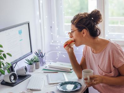 Woman eating while working from home.