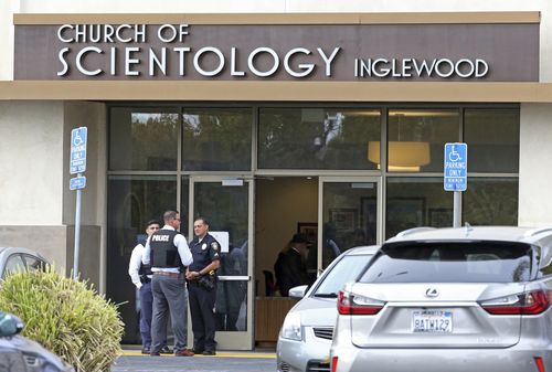 Police stand by outside and investigators work inside the entrance to the Church of Scientology in Inglewood, after a sword wielding man was shot dead by officers. (AP Photo/Reed Saxon)