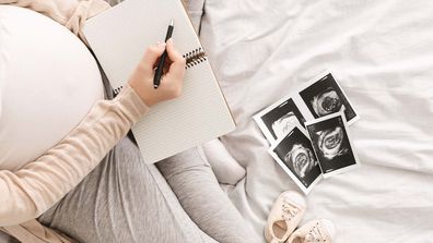 Pregnant woman writing in noteook