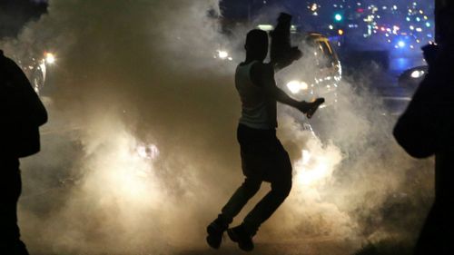 Protesters run when the police shoot tear gas in Ferguson. (AAP)
