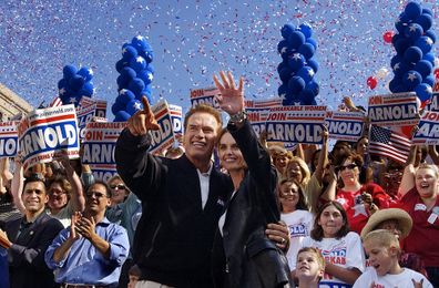 Pictured: October 3, 2003, California gubernatorial hopeful Arnold Schwarzenegger and his wife, Maria Shriver, wave to supporters at the end of a campaign rally on his "California Comeback" bus tour in Modesto, California.