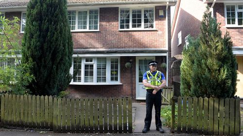 A police officer stands at the front of a residence in Cardiff. (AAP)