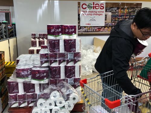 A customer fills his cart with packs of toilet paper at a shopping centre in Sydney.