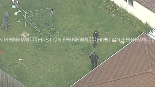 Officers searching a backyard during today's raids. (9NEWS)