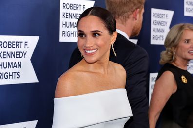 Meghan Markle dressed in white dress, smiling for camera and Robert F. Kennedy Human Rights Ripple of Hope Gala at New York Hilton on December 6, 2022.