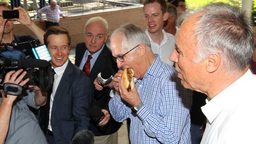 Prime Minister Malcolm Turnbull tucks into a 'Bennelong Bruise' sausage. (AAP