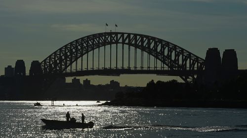 Deux hommes dans un bateau passent le pont du port de Sydney près d'East Balmain pendant le verrouillage de COVID-19 dans tout l'État de NSW. 