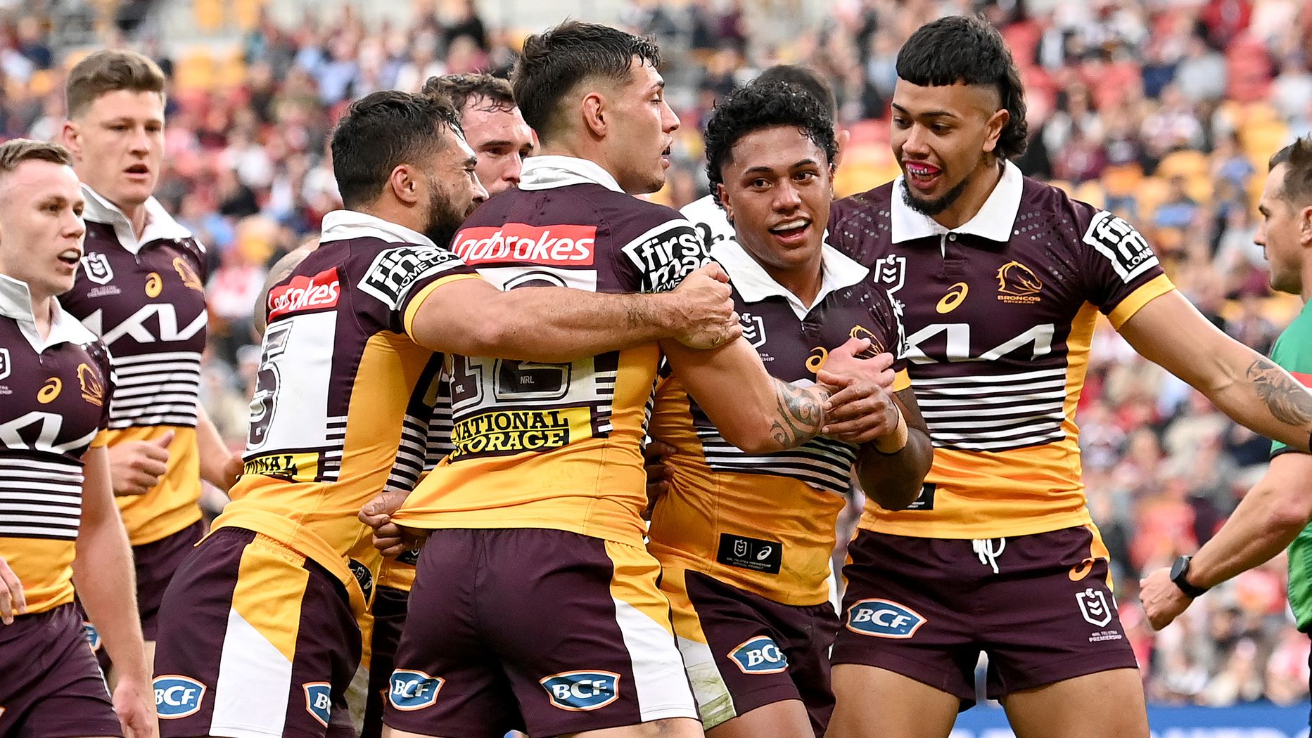 Tesi Niu of the Broncos is congratulated by teammates after scoring a try.