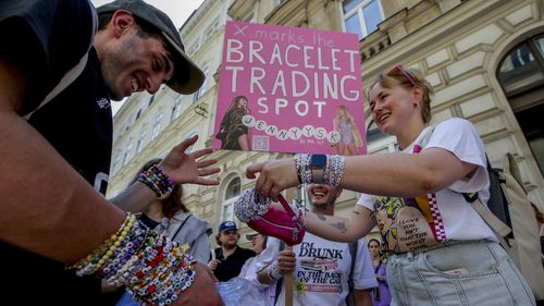 Gli Swifties commerciano braccialetti nel centro di Vienna giovedì 8 agosto 2024. 