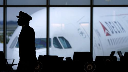 A Delta Airlines pilot wears a face mask to help prevent the spread of the new coronavirus as he walks through a terminal at Hartsfield-Jackson International Airport in Atlanta, Thursday, Feb. 18, 2021. (AP Photo/Charlie Riedel)