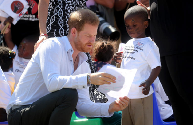 Prince Harry admires a drawing presented to him by the shy child.