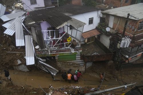 Residents and volunteers remove the body of a landslide victim in Petropolis, Brazil, Wednesday, Feb. 16, 2022. 