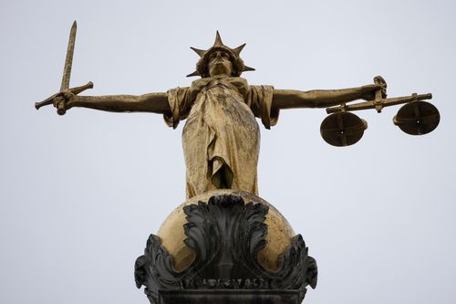 A statue of the Scales of Justice stands above the Old Bailey in London, England.