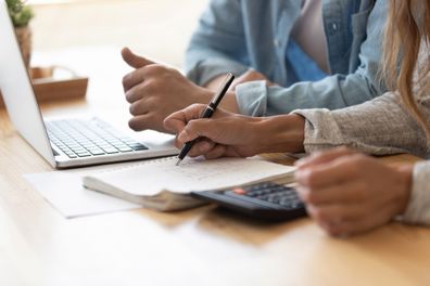 Close up spouses calculating family budget paying utility bills online using laptop, check loan payments, counting expenses. Economy, save money, finances management and planning, paperwork concept