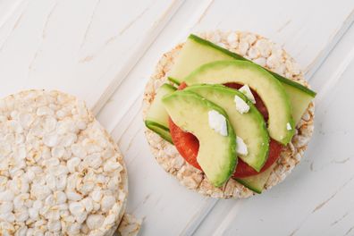 Top view vegan breakfast rice cake / rice cracker with avocado and tomato.