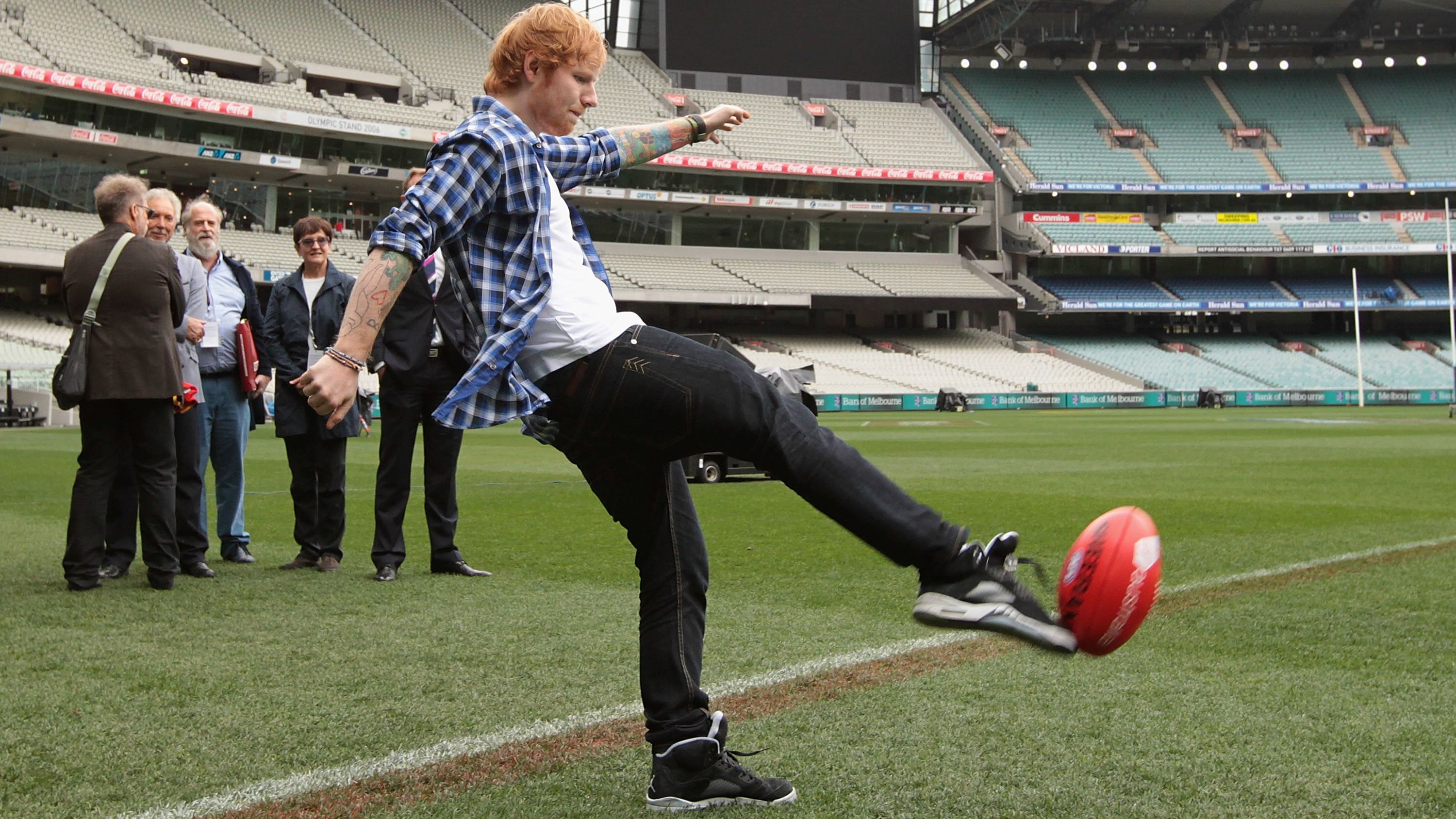 Ed Sheeran kicks a football at the Melbourne Cricket Ground.