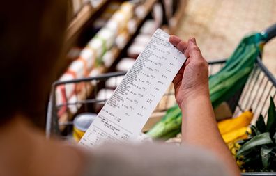 Close-up of a woman looking at a receipt after shopping at the supermarket - cost of living concepts