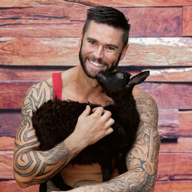 Mitchell Evans poses for the Australian Firefighters Calendar with a baby goat.