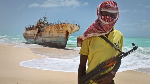 A file photo from 2012 shows a masked Somali pirate near a Taiwanese fishing vessel that washed up on shore after the pirates were paid a ransom and released the crew in Hobyo, Somalia.