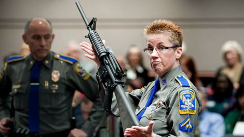 Firearms training unit Detective Barbara J. Mattson, of the Connecticut State Police, holds up a Bushmaster AR-15 rifle, produced by Remington Arms and the same make and model of gun used by Adam Lanza in the Sandy Hook School shooting