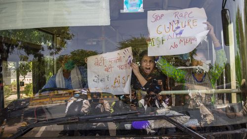 Indian activists hold placards and shout slogans from inside a bus after being detained during a protest in New Delhi.