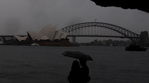 Les gens marchent sous la pluie à la chaise de Mme Macquaries lors d'une activité de tempête accrue à Sydney le samedi 8 octobre 2022