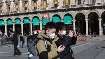 Two tourists are seen wearing a protective mask in the Duomo Square on February 28, 2020 in Milan, Italy
