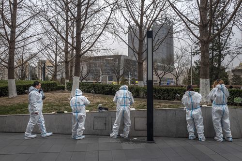 BEIJING, CHINA - MARCH 25: Health workers wear protective suits as they take a break to have dinner near a nucleic acid testing site for COVID-19 in the street on March 25, 2022 in Beijing, China. China has stepped up efforts to control a recent surge in coronavirus cases across the country, locking down the entire province of Jilin and the city of Shenyang and putting others like Shenzhen and Shanghai under restrictions. Local authorities across the country are mass testing as China tries to ma