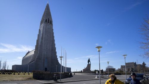 In this photo taken on Wednesday, April 29, 2020, two local boys walk past the empty space in Hallgrimskirkja Church, a popular tourist destination in the center of Reykjavik, Iceland.
