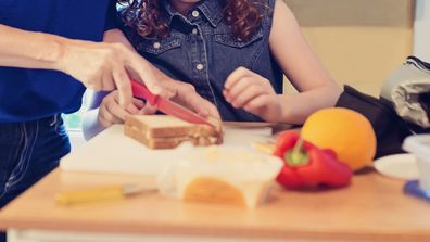 Mother and daughter cutting sandwich.