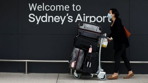 A traveller pushes a luggage cart outside the departure hall of the international terminal of Sydney Airport in Sydney.