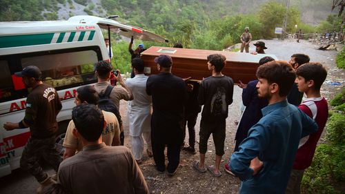 Volunteers load a body into an ambulance after recovering it from a mosque damaged by an Indian missile strike near Muzaffarabad, in Pakistan-administered Kashmir, on May 7, 2025.