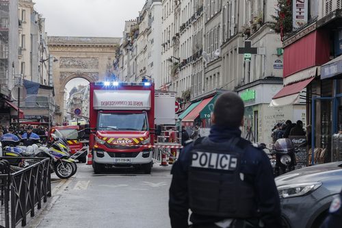 A police officer stands next to the cordoned off area where a shooting took place in Paris, Friday, Dec. 23, 2022.  
