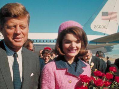 President John F. Kennedy and his wife Jackie, who is holding a bouquet of roses, just after their arrival at the airport for the fateful drive through Dallas.