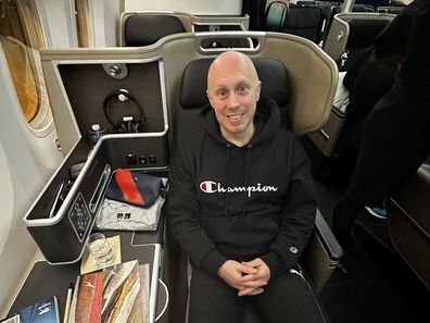 Mark Bowness smiles on a flight to the US before his child's birth.
