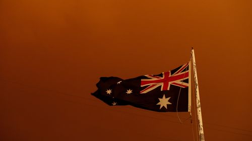 The Australia Flag flies under red skies from the fires on January 04, 2020 in Bruthen Australia, in East Gippsland. (Photo by Darrian Traynor/Getty Images)