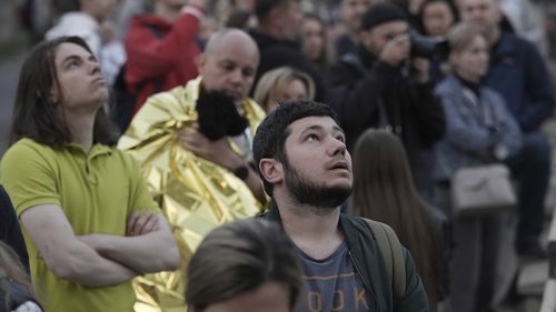 Evacuated residents look at their multi-story apartment building which was damaged during Russian attack in Kyiv, Ukraine, Tuesday, May 30, 2023. 