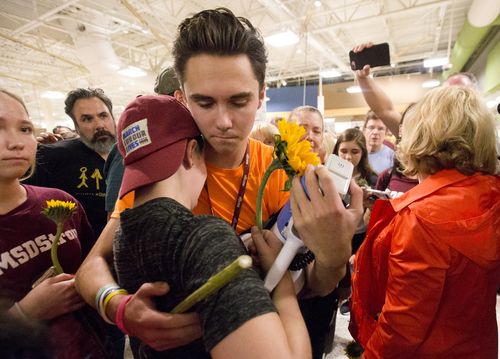 Marjorie Stoneman Douglas High School students David Hogg, center rear, and Caspen Becher, hug after a demonstration at a Publix Supermarket in Coral Springs. Picture: AAP