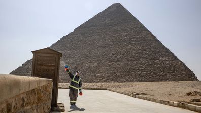 Los trabajadores municipales desinfectan las áreas que rodean el complejo de la pirámide de Giza con la esperanza de frenar el brote del coronavirus en Egipto, el miércoles 25 de marzo de 2020. 