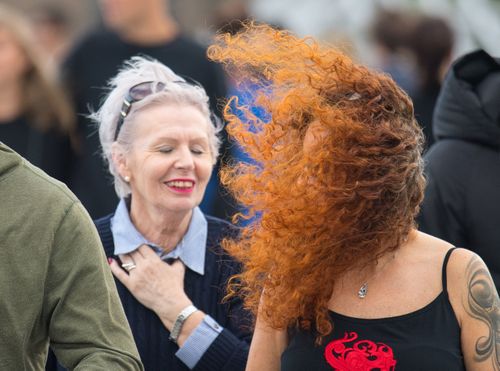 A woman's hair blows into her face as she crosses London Bridge.