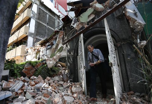 A man walks out of the door frame of a building that collapsed after the earthquake. (AP)
