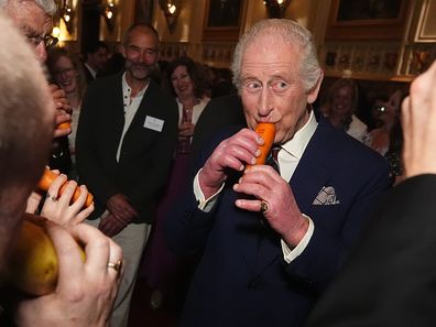 WINDSOR, ENGLAND - APRIL 3: King Charles III plays a carrot with the London Vegetable Orchestra during a reception to recognise those involved in community music across the UK, at Windsor Castle on April 3, 2025 in Windsor, England. The 350 guests include leaders of community music groups and music-related projects, many of whom are volunteers. (Photo by Aaron Chown - WPA Pool/Getty Images)