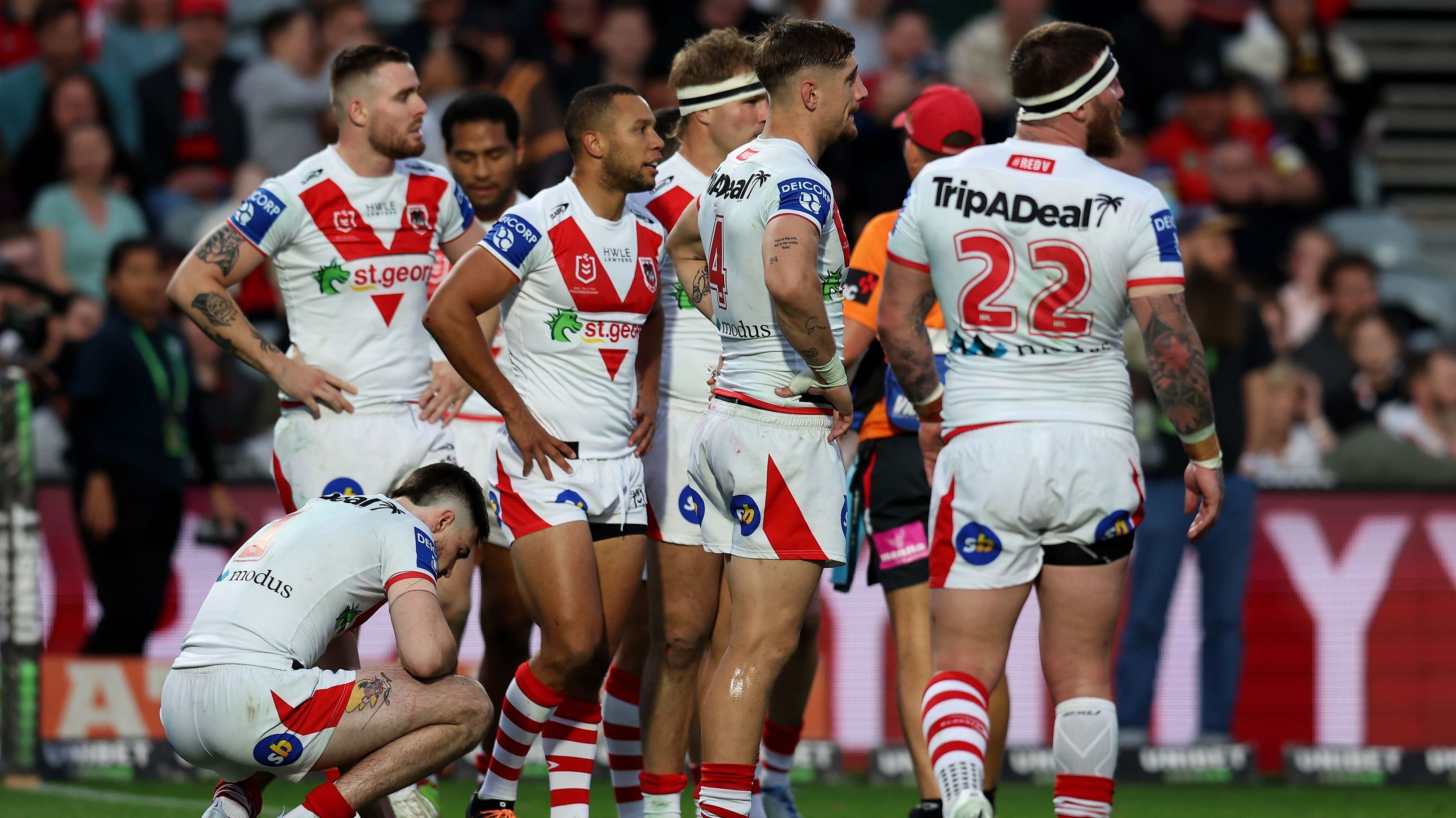 Dragons players huddle together following a Roosters try.
