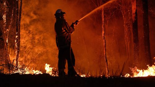 NSW RFS fire fighters work through the night to prevent a flare up from crossing the Kings Highway in between Nelligen and Batemans Bay.  NSW RFS has called for all tourists to leave the area ahead of this weekends hazardous fire conditions. Batemans Bay, NSW. 2nd January, 2020. Photo: Kate Geraghty