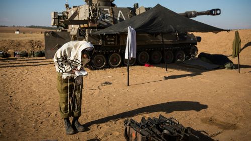 An Israeli soldier prays after helping fire artillery shells into Gaza from Sderot, Israel. The body count in Gaza has reach over 200 people. Picture: Getty Images