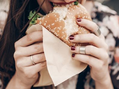 woman eating hamburger with beetroot slices