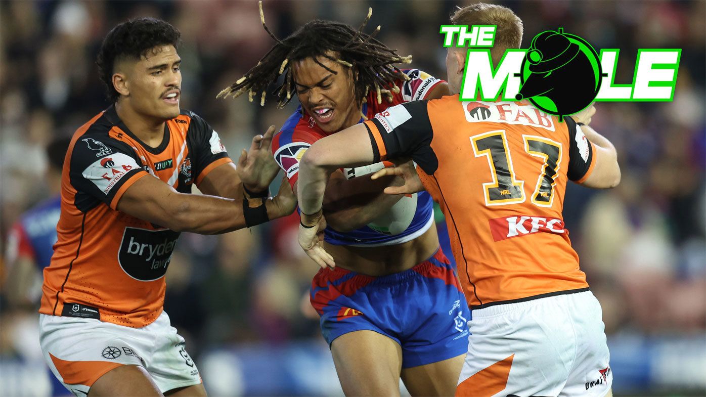 Knights winger Dominic Young attempts to break the tackle of two Wests Tigers defenders.