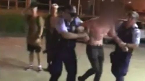 The shirtless 17-year-old swears at police as they try to detain him. (9NEWS)