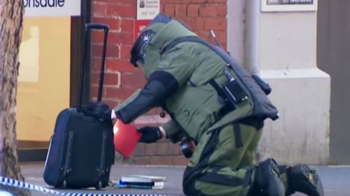 A bomb squad member examines a suspicious bag.