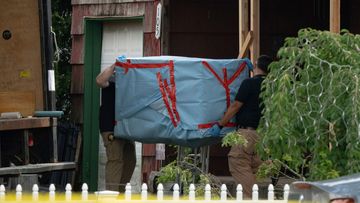 New York State police officers carry out an large item from the home of Rex Heuermann